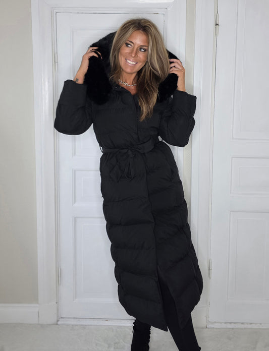 Lång quiltad jacka med huva, fuskpäls och knytbälte